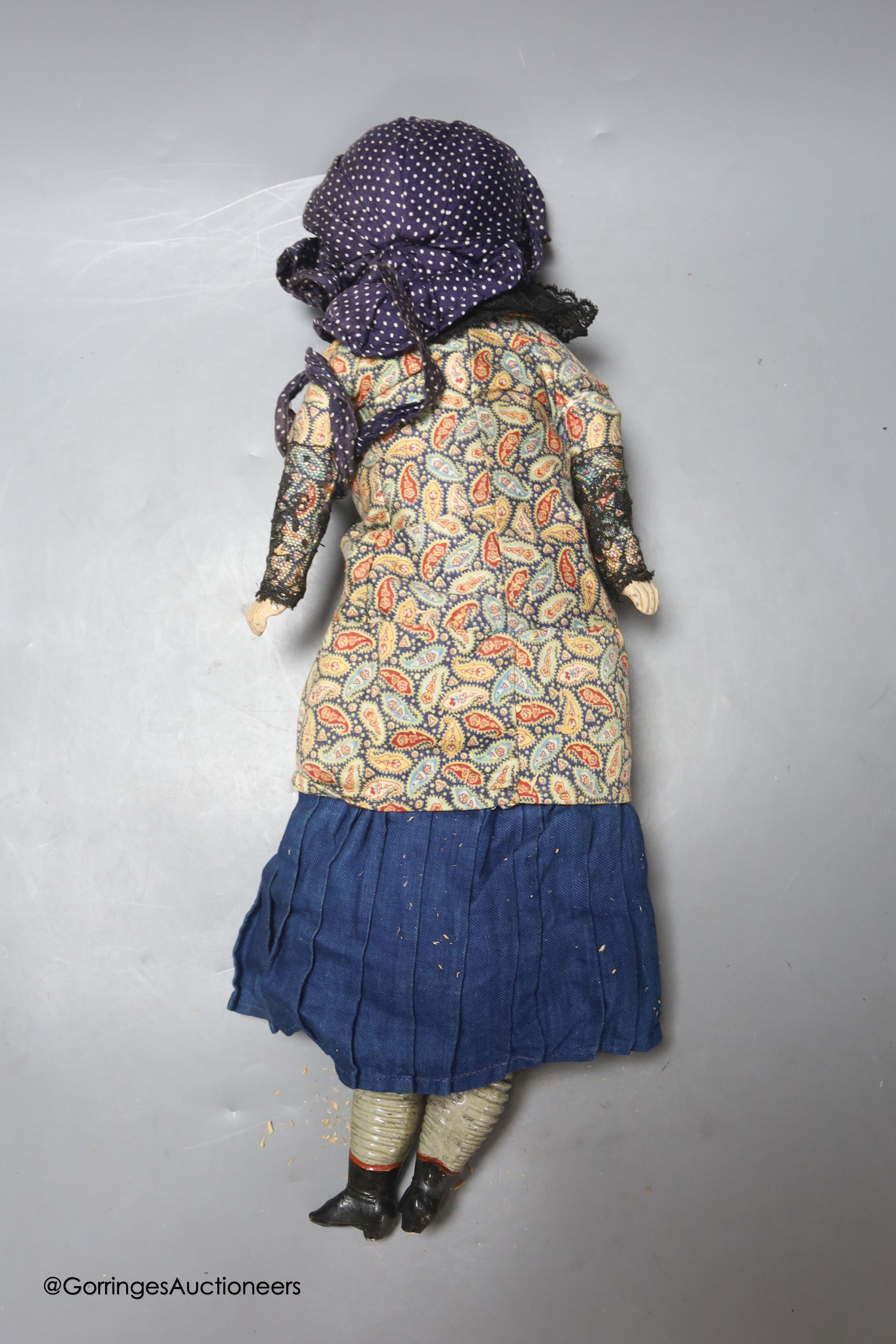 A wax composition doll, In early clothing, one leg detached but present, 18ins